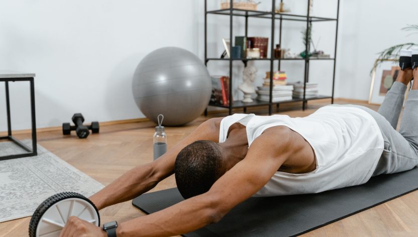 A man performs an ab roller workout indoors, emphasizing healthy lifestyle and fitness. — 9 Online Fitness Equipment Retailer