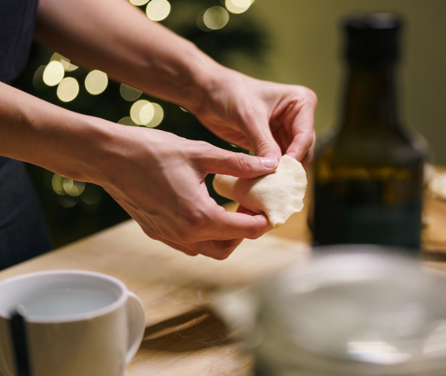 Hands crafting dumplings in a cozy kitchen setting with warm festive lights. Perfect for holiday cuisine. — A BEGINNER'S GUID