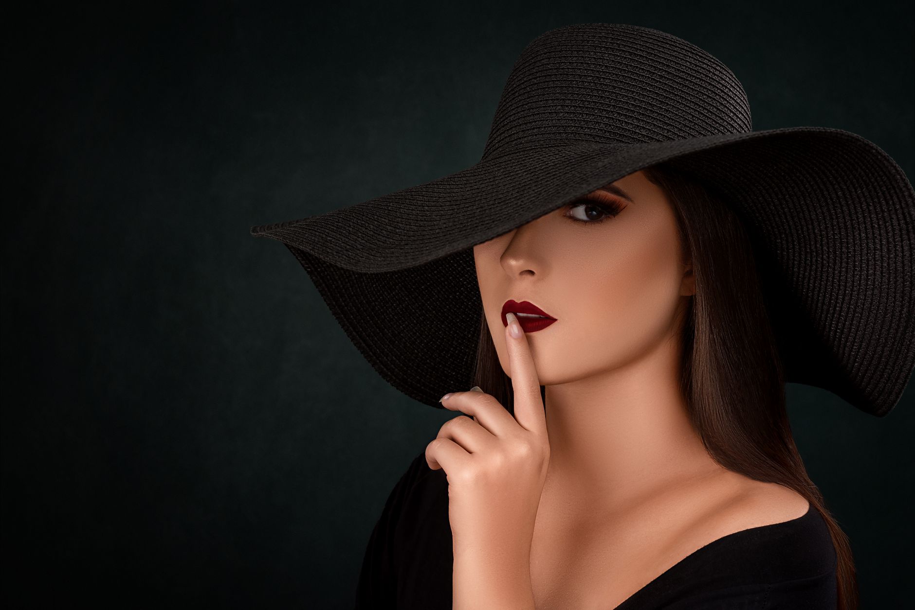 Mysterious woman in black hat making a hush gesture with dark background. — Are You Using These Effective Beauty Tips For You