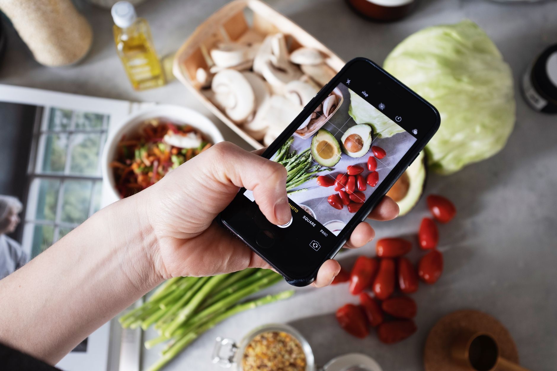 Hand holding smartphone capturing photo of fresh vegetables on a kitchen counter. — Delicious and Nutritious: What Is Plant B