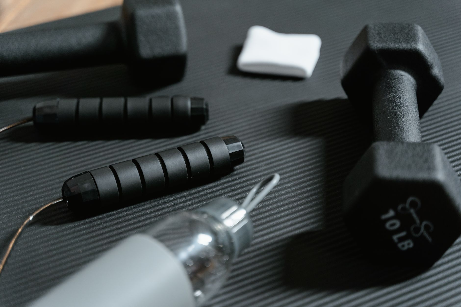 Dumbbells, jumping rope, and water bottle on a yoga mat for home workout routine. — Important Ways to Boost Women's Health