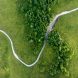 Aerial view of a winding dirt road through lush green fields and trees.